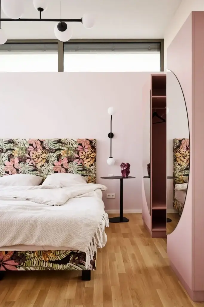 Doppelbett mit Blumenkopfteil, schwarzer Wandleuchte und Garderobennische in der Ferienwohnung
