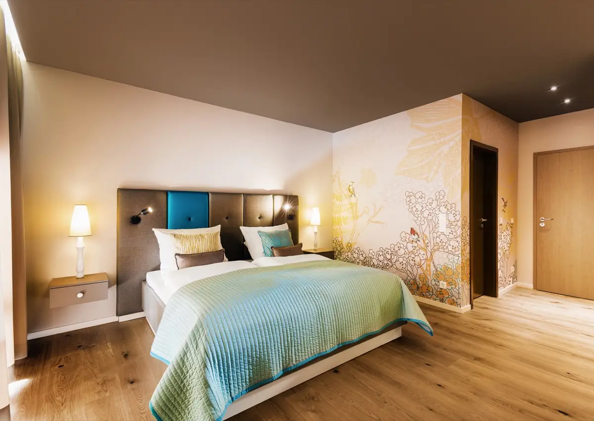 Hotelzimmer im Hotel Taufstein mit Polsterbett, gemalter Blütenwand und Eichenboden