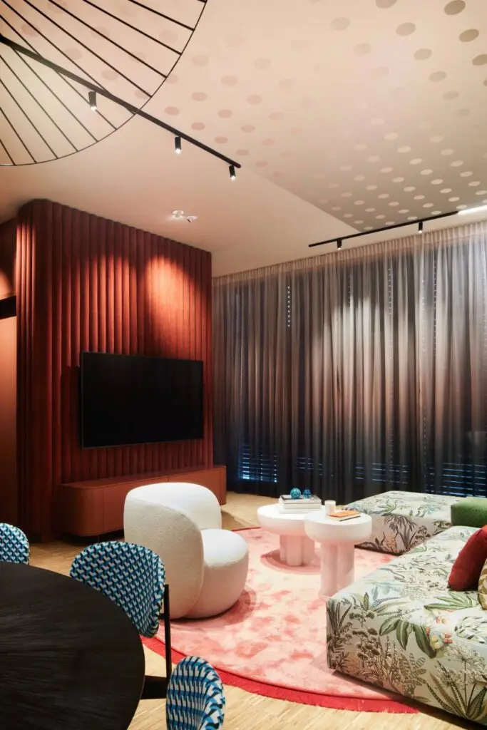 Rote Lamellenwand mit Fernseher, Ombré-Vorhängen und Sitzgruppe im Business Apartment