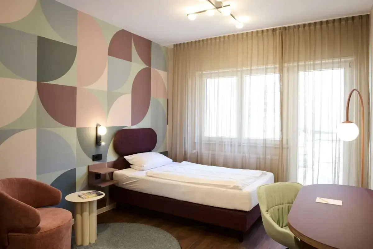 Gästezimmer mit Doppelbett, Musterwand und Vorhängen im Gästehaus II