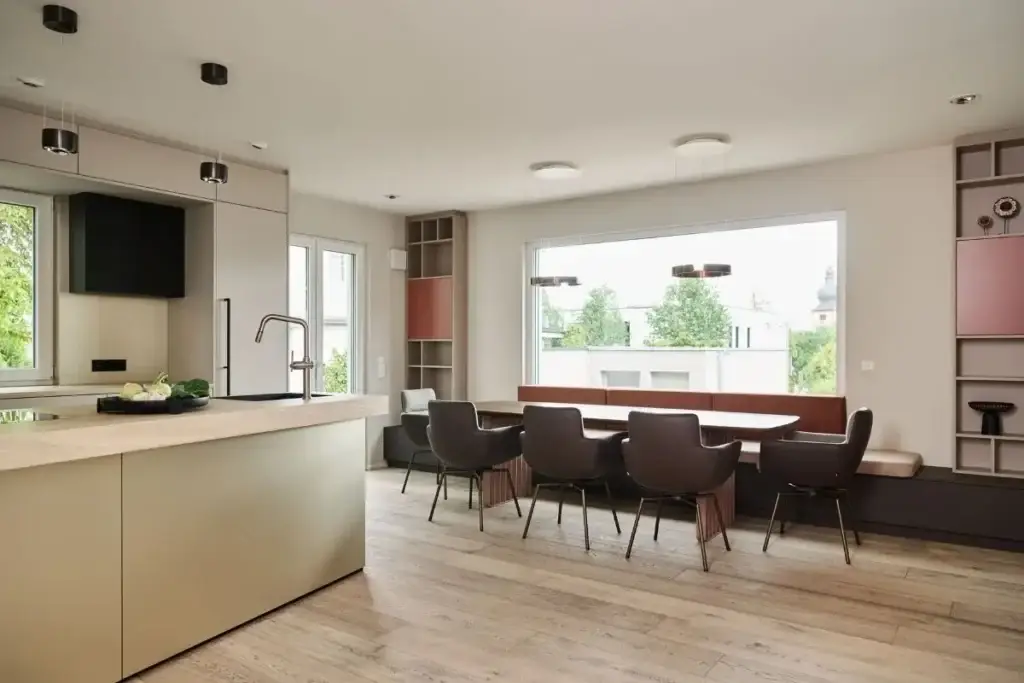 Kücheninsel und Esstisch mit dunklen Lederstühlen vor großem Fenster im Haus R in Fulda