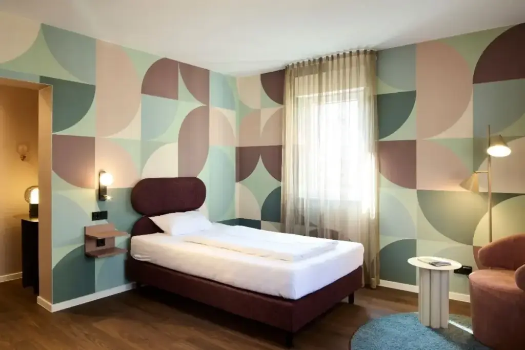 Gästezimmer mit Bett vor gemusterter Wand im Gästehaus II