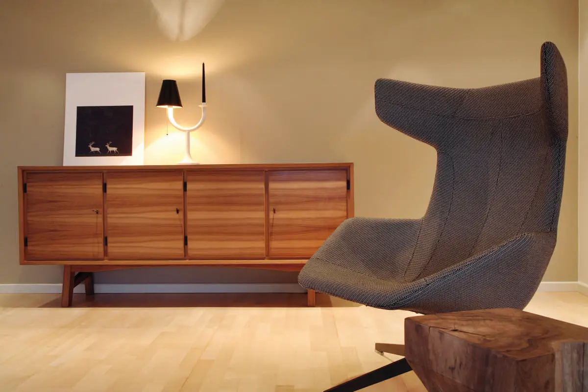 Sideboard aus Holz und Sessel im Wohnbereich der Wohnung D