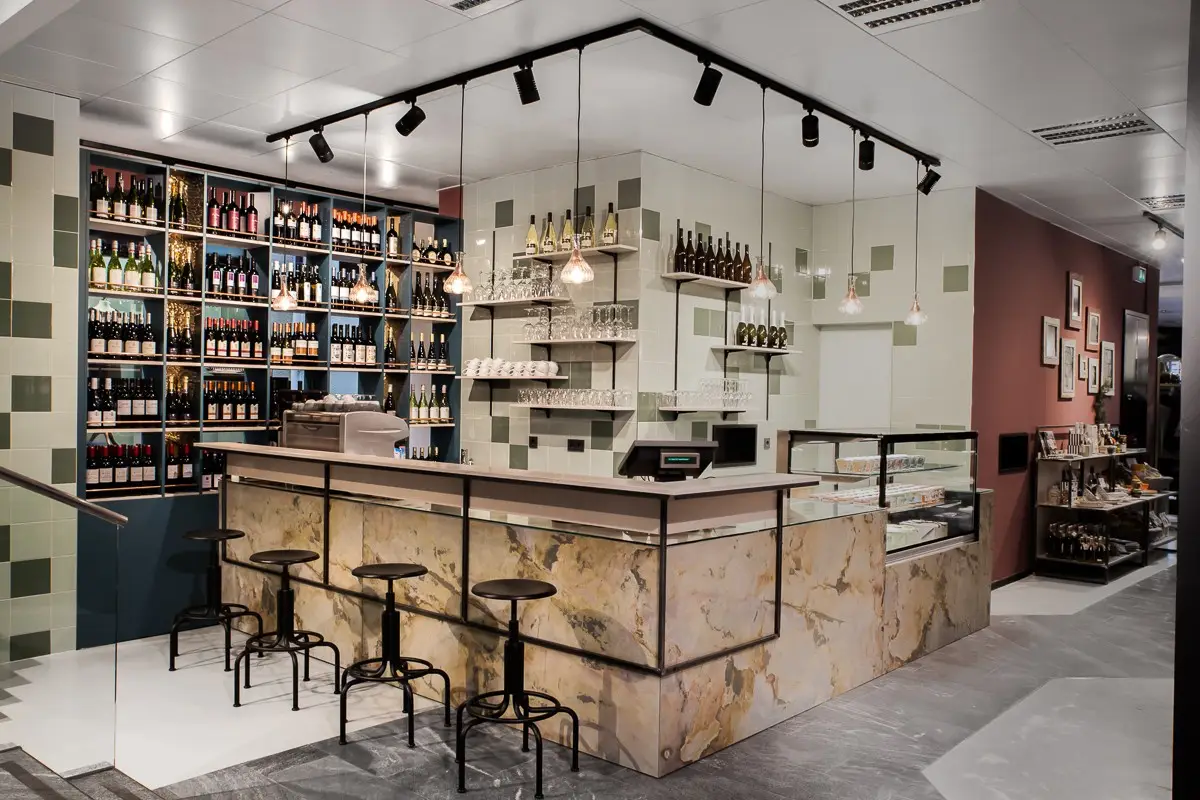 Theke mit Echtsteinfurnier und Regalwand mit Feinkost bei Bruno's Finest Food