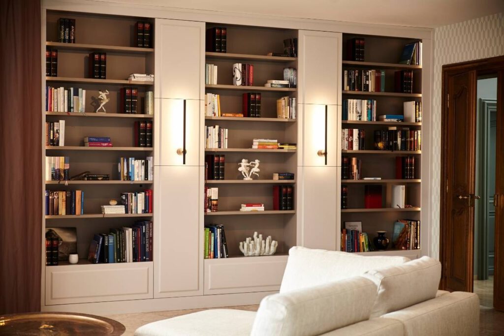 Raumhohes Bücherregal mit integrierten Leuchten hinter weißem Sofa in der Villa A