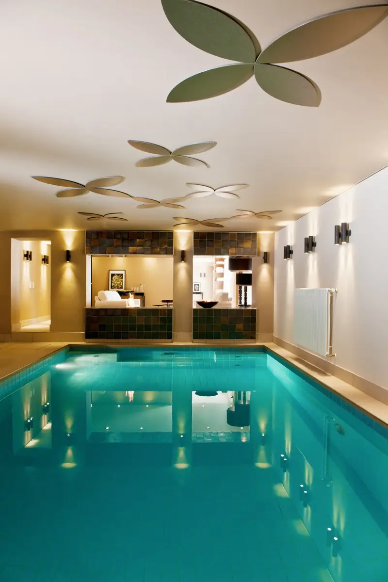 Hallenbad im Hotel Taufstein mit türkisem Becken, Holzeinbauten und Deckenleuchten in Blütenform