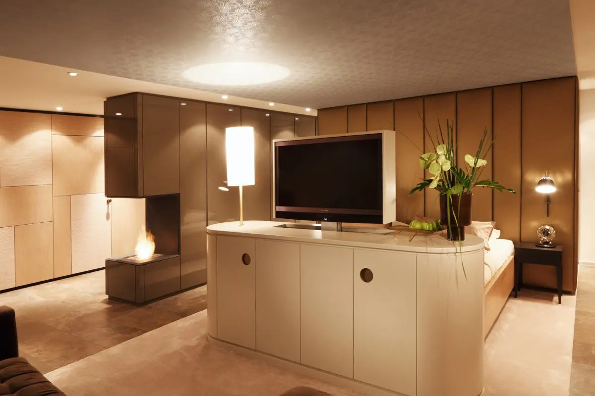 Halbrundes Sideboard mit Fernseher vor dem Bett in der Suite A