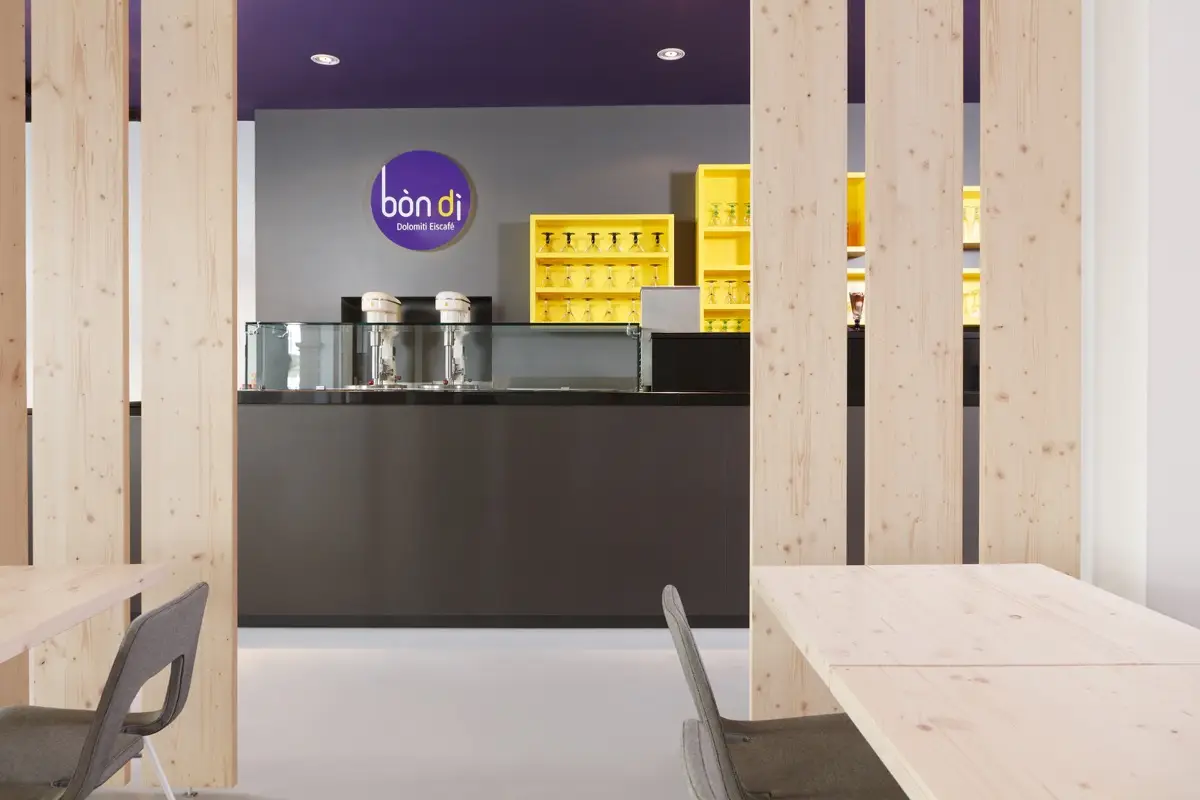 Theke des Eiscafés Bondi mit Lamellen aus Fichte und gelben Regalen