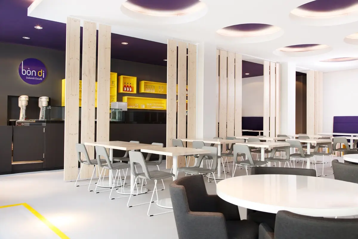 Gastraum des Eiscafés Bondi in Fulda mit weißen Tischen, hohen Polsterbänken und violetter Decke