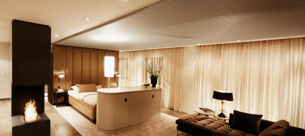 Private Suite in der Rhön mit Bett vor raumhoher Polsterwand, Wandverkleidung und TV-Möbel