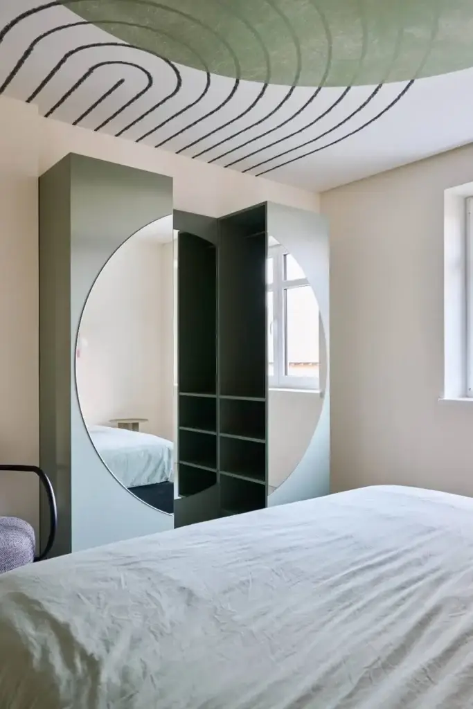 Salbeigrüner Kleiderschrank mit rundem Spiegel im Schlafzimmer einer Ferienwohnung der Villa Haag