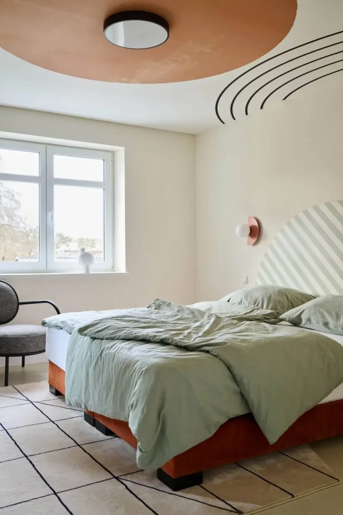 Schlafzimmer mit salbeigrüner Bettwäsche und terrakottafarbenem Deckenkreis in der Villa Haag