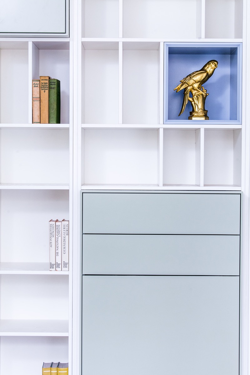 Weiße Regalwand aus dem Regalsystem H mit offenen Fächern und hellblau lackierten Einschüben
