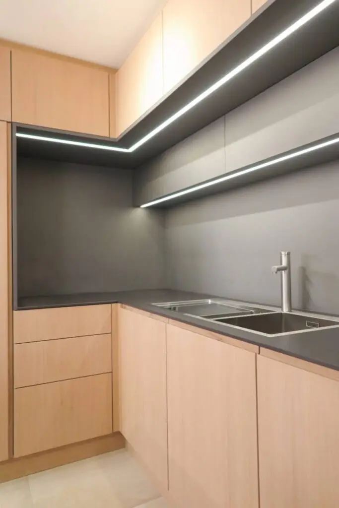 Küchenecke mit Eichenfronten, dunkler Rückwand und LED-Lichtleiste im Haus R in Kassel