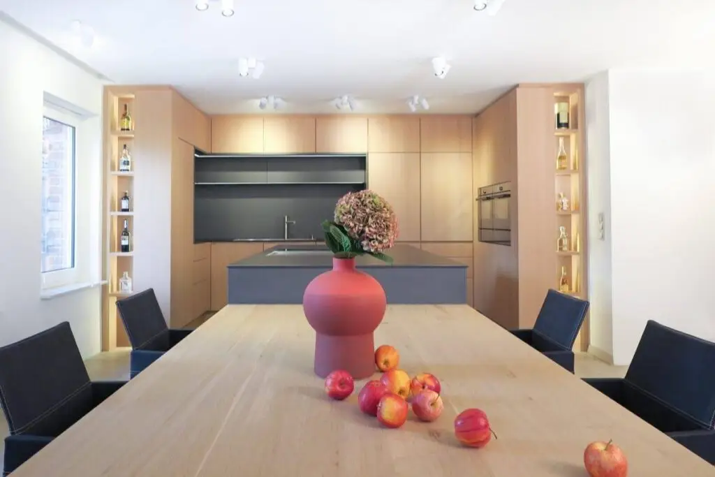 Holztisch mit roter Vase vor offener Küche in Eiche im Haus R in Kassel