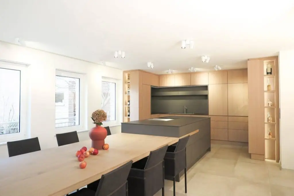 Langer Holztisch mit dunklen Stühlen vor Küche in Eichenholz im Haus R in Kassel