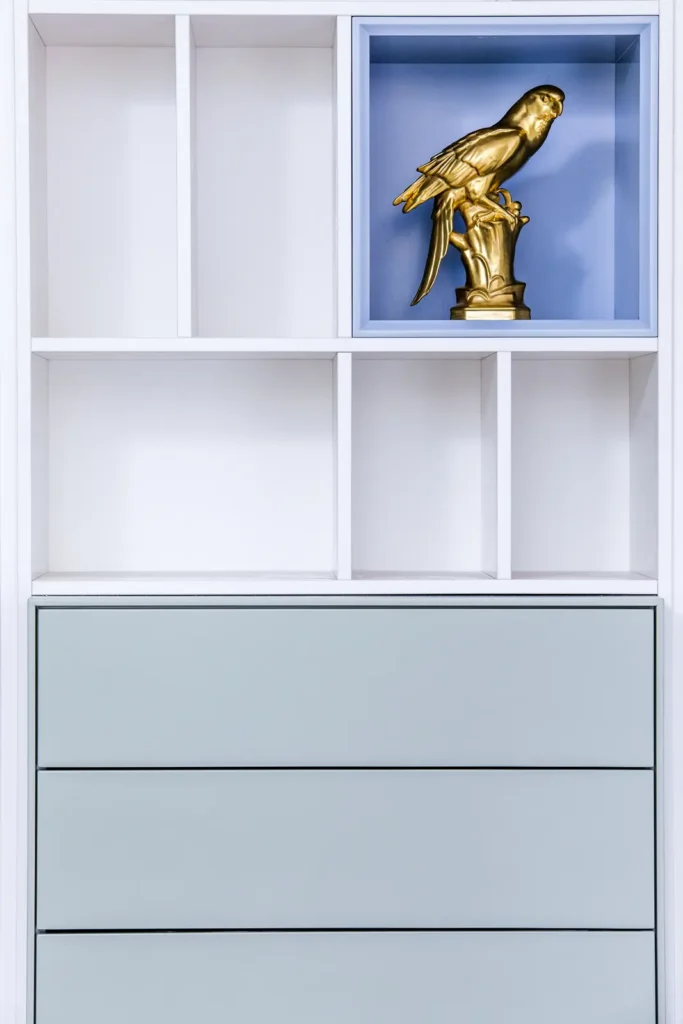 Detail des Regalsystems H: hellblau lackiertes Fach über salbeigrünen Schubkästen in einer weißen Regalwand