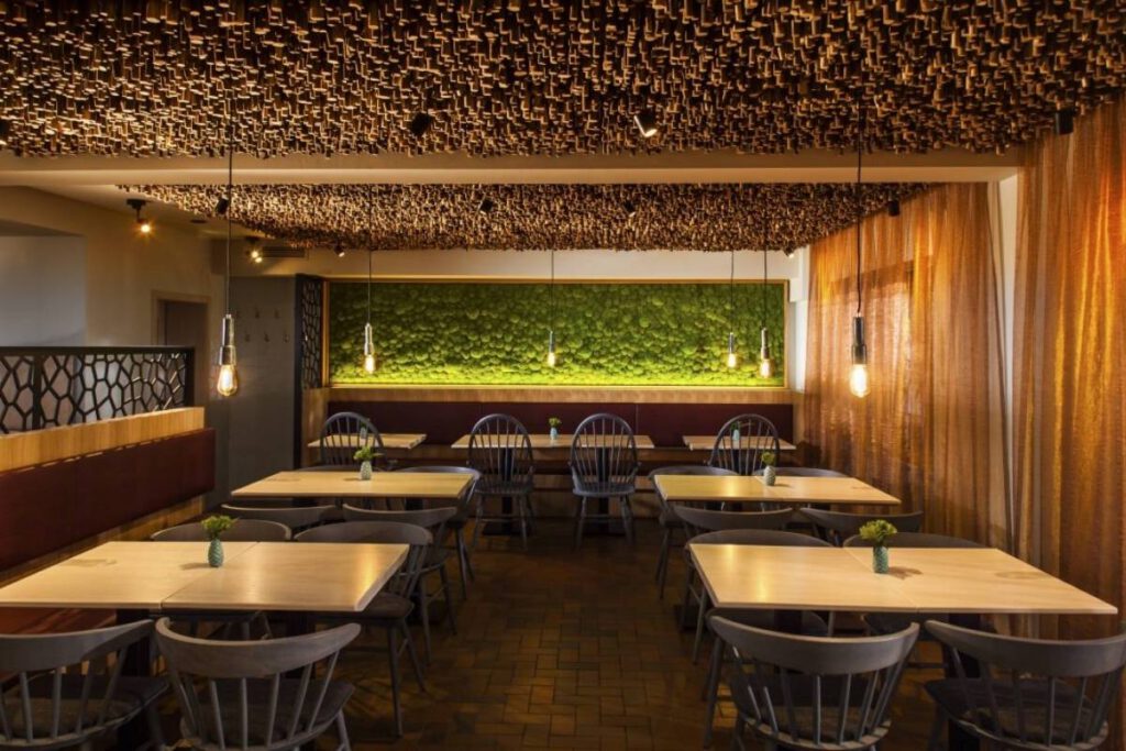 Gastraum mit Holzdecke, Mooswand und hellen Holztischen im Restaurant II des Hotel Taufstein in Kalbach