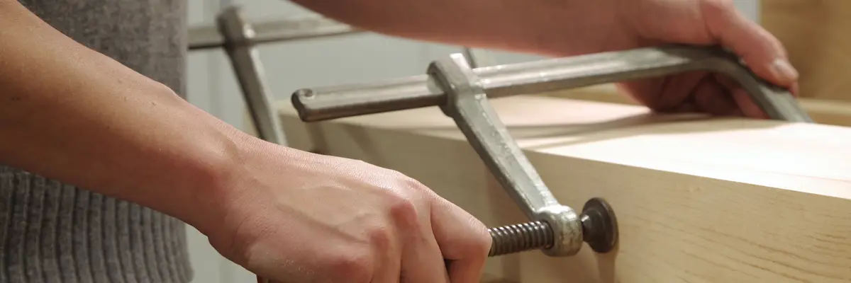 Schraubzwinge an einem Werkstück aus Holz in der Werkstatt
