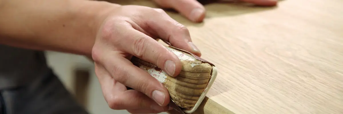 Hand prüft eine geschliffene Holzoberfläche